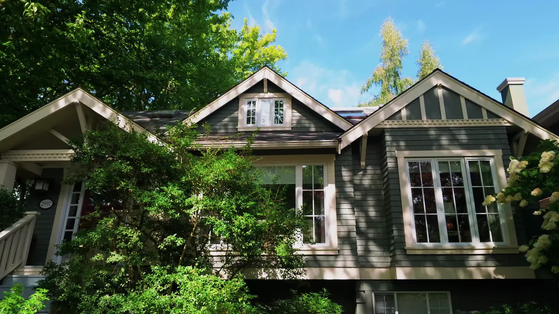 Exterior of a Vancouver home framed by mature trees, filmed by Joel